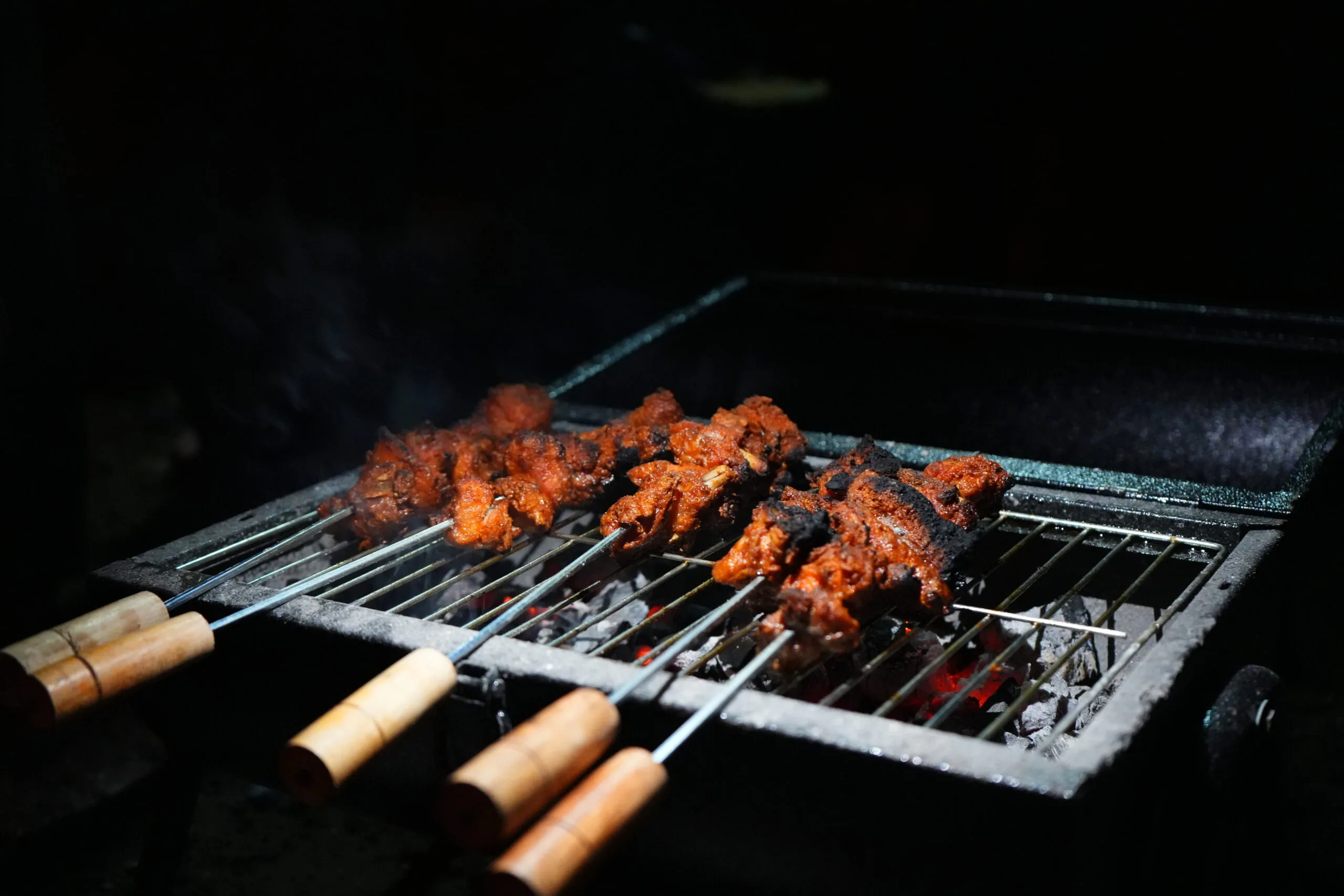 Skewers grilling over coals at the farm barbeque
