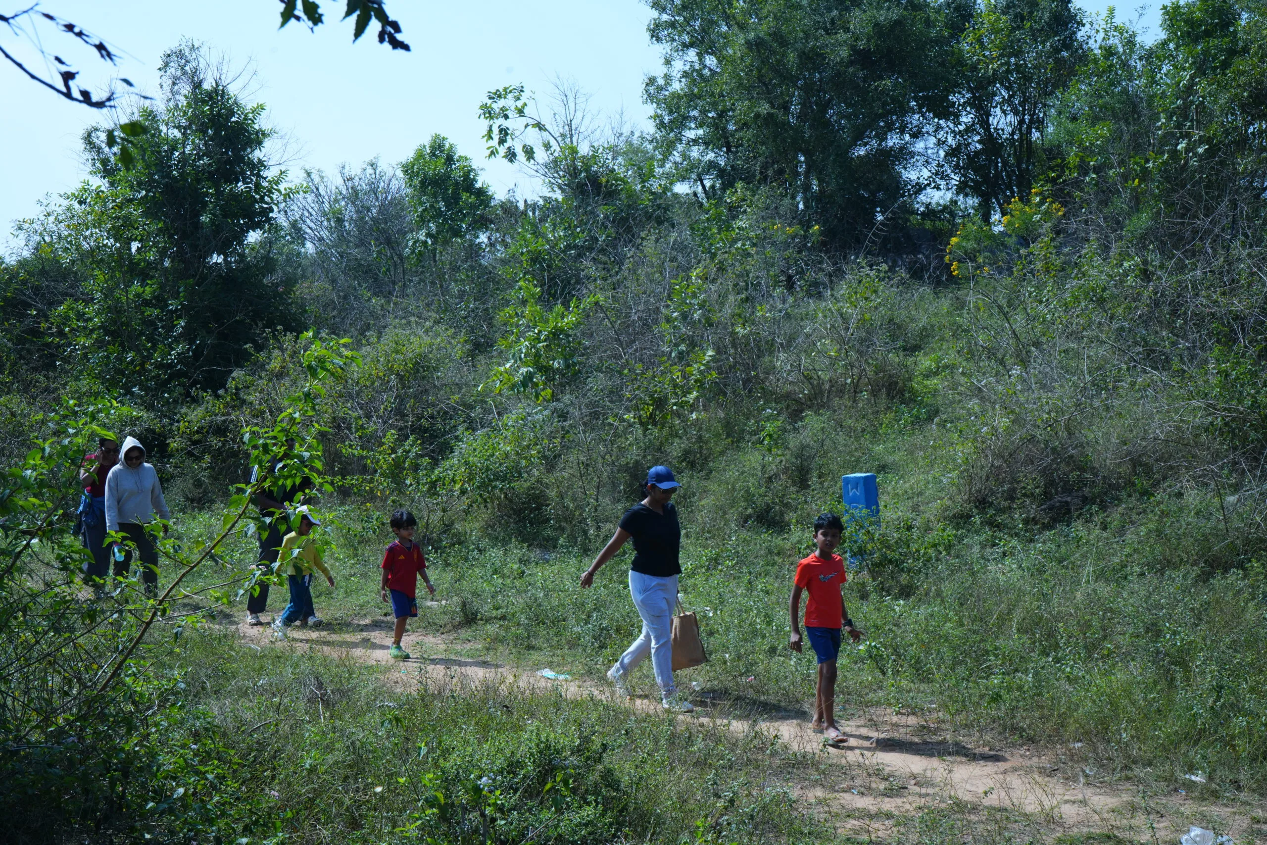 Trekkers walking a scrub-forest trail near the farm