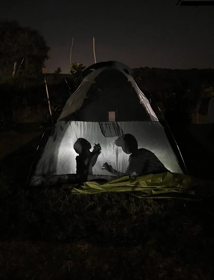 A lit tent after dark, guests making shadow puppets inside
